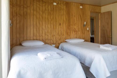 2 łóżka w pokoju z drewnianymi ścianami w obiekcie La Casona, Baño Privado w mieście Villa Cerro Castillo