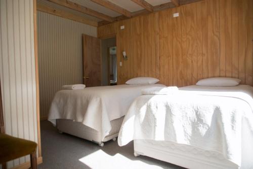 two beds with white sheets in a room at La Casona, Baño Privado in Villa Cerro Castillo