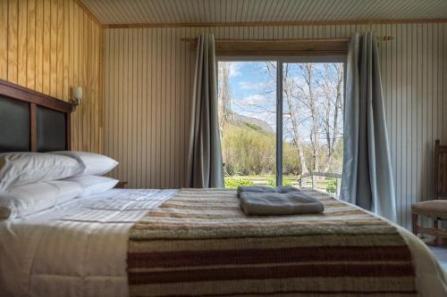 ein Schlafzimmer mit einem großen Bett und einem großen Fenster in der Unterkunft La Casona, Baño Privado in Villa Cerro Castillo