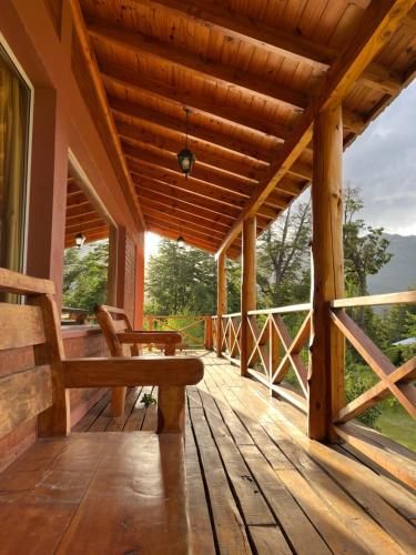 Las Liebres Casa de Montaña في الهويو: شرفة مع مقعد على سطح خشبي