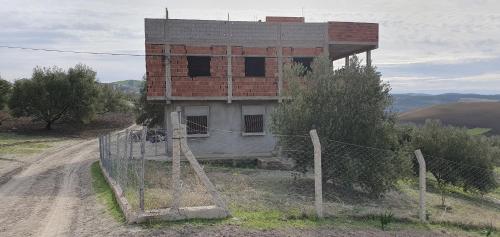 un edificio al lado de un camino de tierra con una valla en BADR ABDELLAH en Taounate