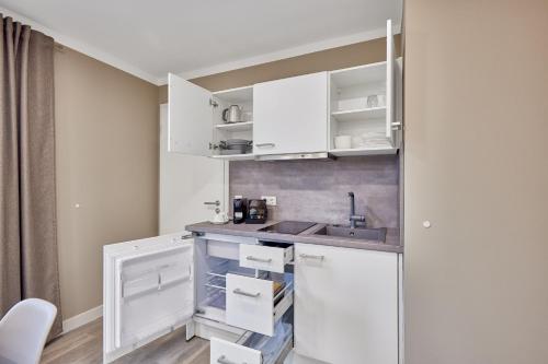 a kitchen with white cabinets and a sink at Boardinghotel Premium Heidelberg in Heidelberg