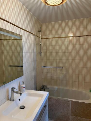 La salle de bains est pourvue d'un lavabo, d'une baignoire et d'un miroir. dans l'établissement Ma Bohème - Jardin en Centre historique, à Honfleur