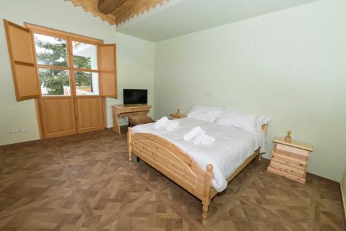 um quarto com uma cama com lençóis brancos e uma televisão em La Valle del Gran Sasso em Assergi