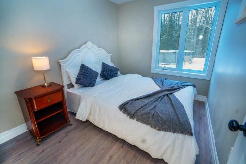a bedroom with a bed with a nightstand and a window at Mountain House in the Heart of Haliburton, Mins to Lake in Haliburton