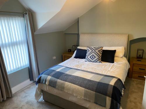 een slaapkamer met een bed met kussens en een raam bij Victorian South Belfast area Lisburn Road 3 Double Bedrooms - Great Transport Links in Belfast