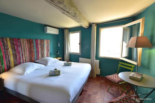 ein Schlafzimmer mit einem großen weißen Bett und einem Tisch in der Unterkunft Les Maisons Mado in Venasque