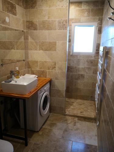 een badkamer met een wastafel en een wasmachine bij Appartement entier dans dépendance in Saint-Morillon