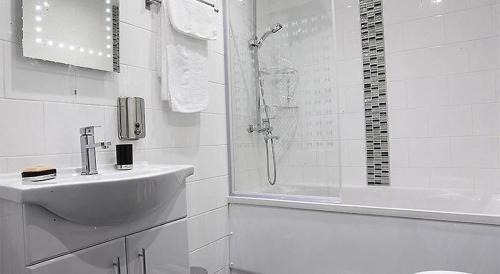 een witte badkamer met een wastafel en een douche bij Well located Northern Quarter Apartment sleeps Upto 6 in Manchester