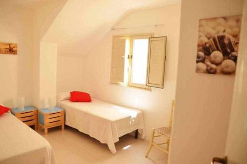 een witte kamer met een bed en een raam bij Casa delle Palme sulla spiaggia in Marzamemi