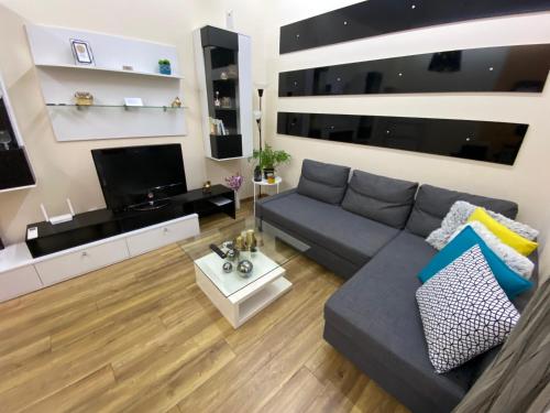 a living room with a gray couch and a flat screen tv at Cozy apartment in downtown Sofia - Tsar Samuil Street in Sofia