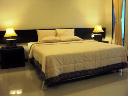 a bedroom with a large bed with two lamps at 21 Lodge in Nusa Dua