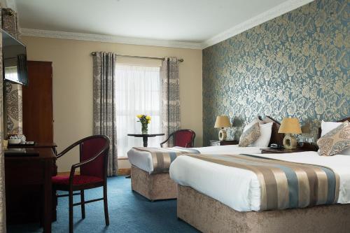 a hotel room with two beds and a desk at Holyrood Hotel - Leisure Centre & The Spa at Orchids in Bundoran