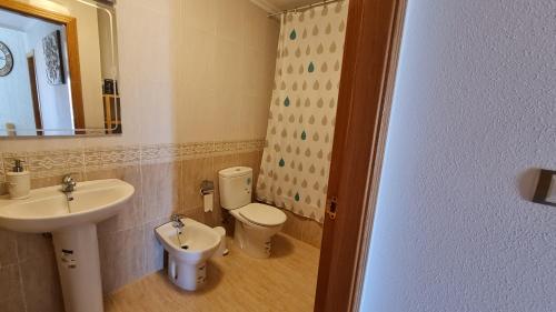 a bathroom with a sink and a toilet and a mirror at Tirreno Vacances in San Juan de los Terreros