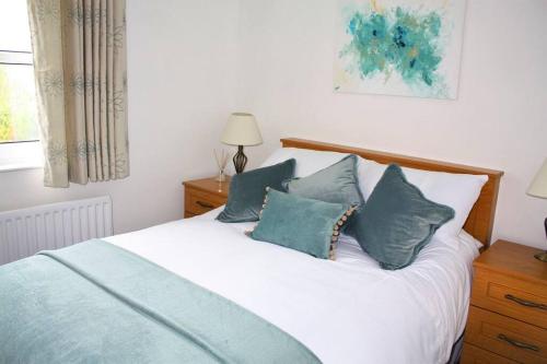 a bedroom with a white bed with blue pillows at Harbour View House in Ballycastle