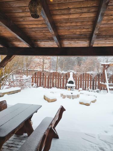 a snow covered patio with a picnic table and benches at Domek Drwala k. Karpacza in Sosnówka