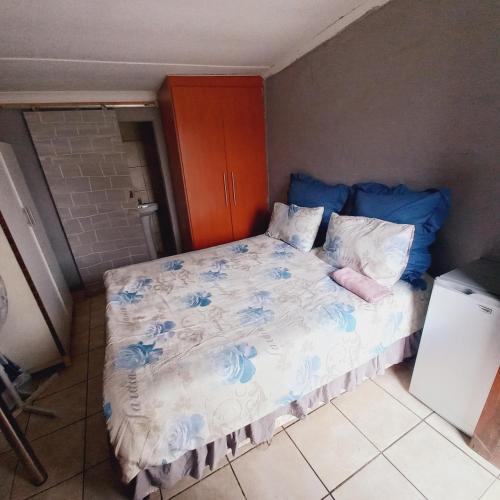 a small bedroom with a bed with blue flowers at Alo guesthouse in Pietermaritzburg