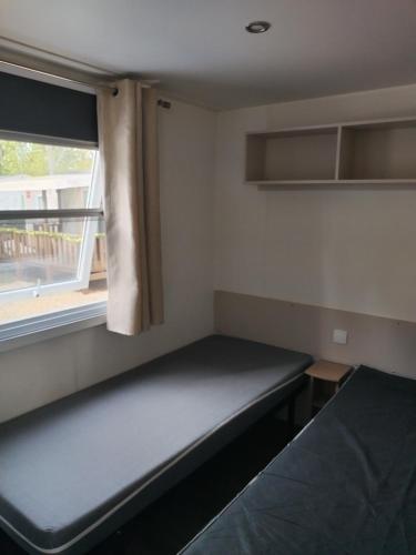 une petite pièce avec un lit et une fenêtre dans l'établissement Les sables du midi, à Sérignan