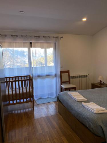 um quarto com uma cama e uma janela com uma cadeira em Casa de Casarelhos - Gerês em Gerês