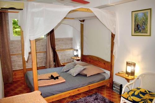 a bedroom with a canopy bed with a hat on it at Le Jardin du Petit Macabou in Le Vauclin