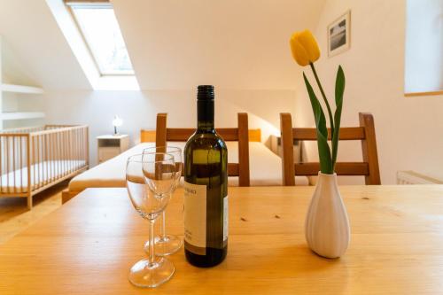 a bottle of wine and two glasses on a wooden table at Penzion U hájovny u pískoven - Vlkov in Vlkov