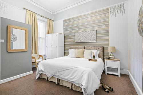 a bedroom with a large white bed and a mirror at Kethla House in Torquay