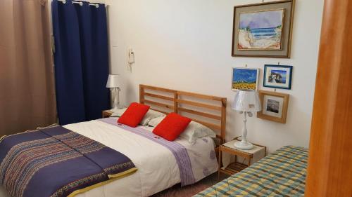 una camera con un letto con due cuscini rossi di Locazione Turistica Conca d'Oro a Crispiano