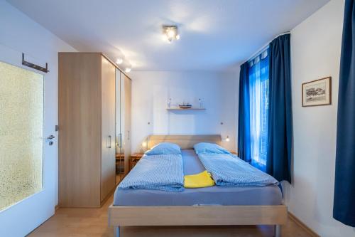 een slaapkamer met een bed met blauwe lakens en een raam bij Nordland Appartements - Wohnung Amrum in Wyk auf Föhr