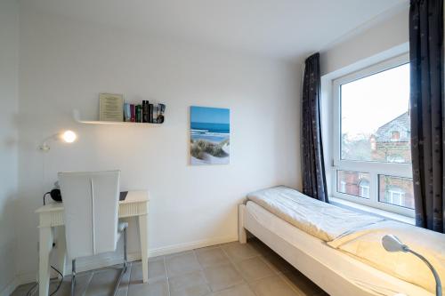 een slaapkamer met een bed, een bureau en een raam bij Nordland Appartements - Wohnung Hooge in Wyk auf Föhr
