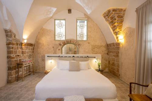 a bedroom with a white bed in a room with stone walls at Akotika boutique in ‘Akko