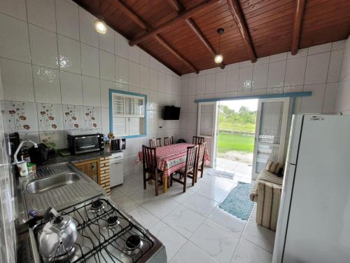 a kitchen with a refrigerator and a table with chairs at Casa temporada praia da galheta 3 in Laguna