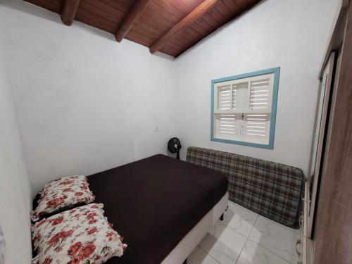 um pequeno quarto com uma cama e uma janela em Casa temporada praia da galheta 3 em Laguna