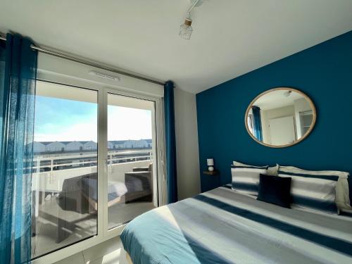 a bedroom with a bed and a mirror and a balcony at L'intemporel plage - Malo'Cation in Dunkerque
