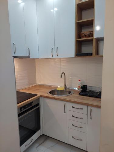 eine Küche mit weißen Schränken und einem Waschbecken in der Unterkunft Sunrise Apartments sa garažom in Banja Luka