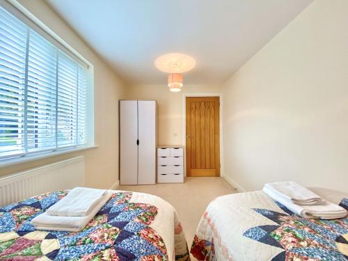 a bedroom with two beds and a window at Peacock Court in Corsham