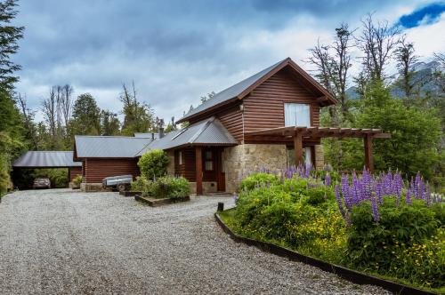 a log cabin with a gravel driveway and flowers at BOG Ocrehue - Cabanas in Villa La Angostura