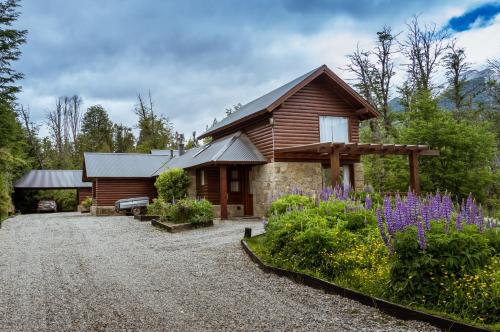 Cabaña de madera con entrada de grava y flores en BOG Ocrehue - Cabanas en Villa La Angostura