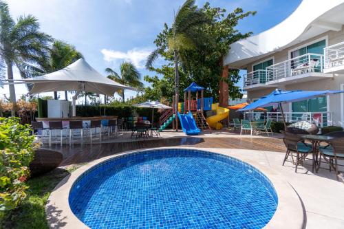 a swimming pool in front of a house with a playground at Hotel Paradiso del Sol in Cabo Frio