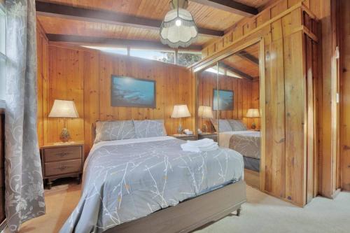 1 Schlafzimmer mit einem Bett, 2 Lampen und Holzwänden in der Unterkunft Rustic cottage on Canal Lake in Carden