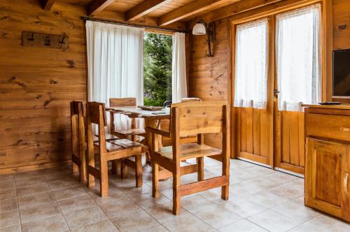 comedor con mesa, sillas y ventana en BOG Ocrehue - Cabanas en Villa La Angostura