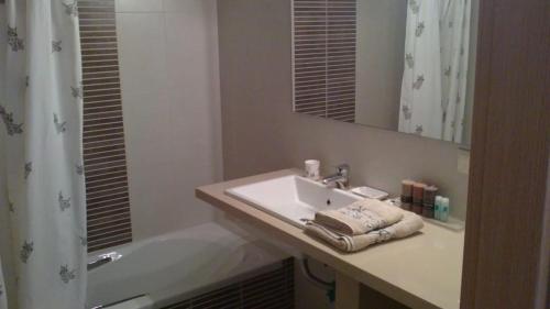 La salle de bains est pourvue d'un lavabo, d'une baignoire et d'un miroir. dans l'établissement Villa apartment with private garden near the beach, à Drepano