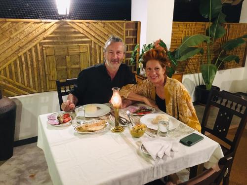 a man and woman sitting at a table with food at Vala House in Cherai Beach