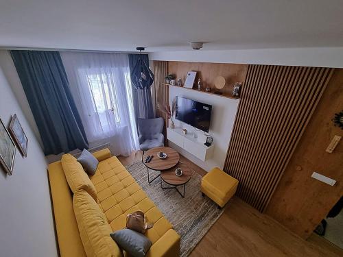 a living room with a yellow couch and a table at Vila Jahor - Apartmani Trifković in Jahorina