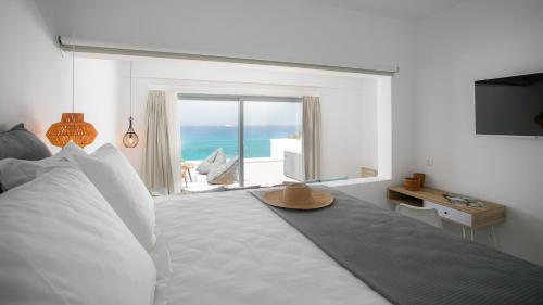 1 dormitorio con 1 cama y vistas al océano en Seanfinity Beachfront Suites en Mikri Vigla
