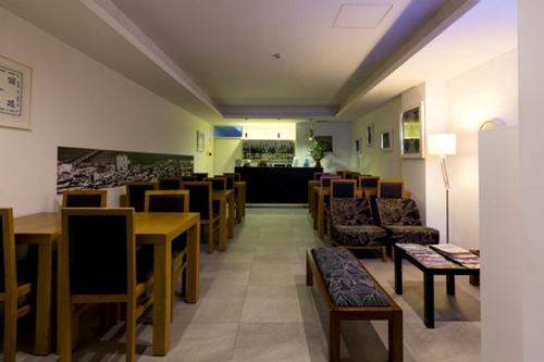 a restaurant with tables and chairs and a bar at Hotel Laranjeira in Viana do Castelo