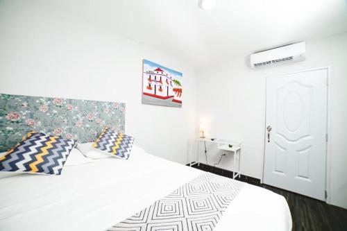 1 dormitorio con cama blanca y almohadas en JM GUESTHOUSE, en Santo Domingo