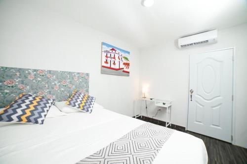 a bedroom with a white bed with pillows at JM GUESTHOUSE in Santo Domingo