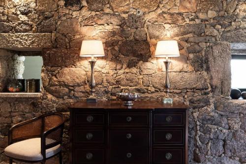 uma parede de pedra com duas lâmpadas numa cómoda em Villa Medroa em Faia