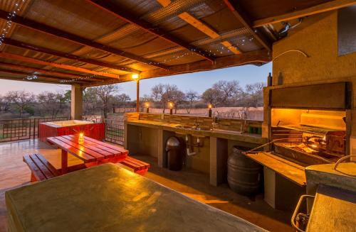 an outdoor kitchen with a table and a grill at Doornkom in Marloth Park
