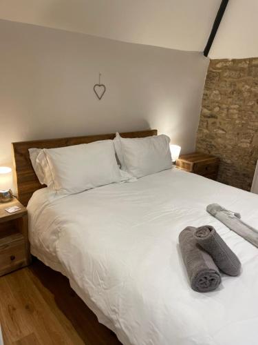 a bedroom with a white bed with towels on it at Cotswold Coombe Cottage in Wotton under Edge